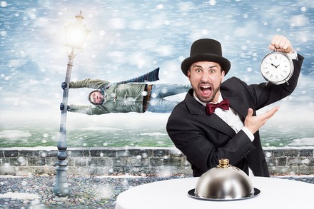 Mann im Anzug, der auf Uhr deutet und anderer Mann im Hintergrund, der fast vom Wind weggeweht wird