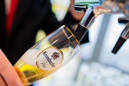 Mann füllt Bier in ein Krombacher Pils Glas