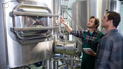 Brauer zeigt auf Tank in Brauerei