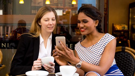 Zwei Frauen schauen im Cafe ins Handy