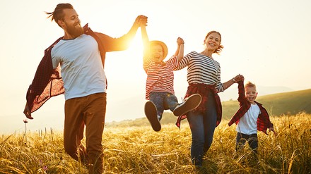 Familie läuft lachend über Wiese
