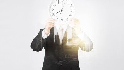 Mann hält Uhr vor seinen Kopf
