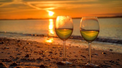 Wein in Glas am Strand im Abendrot