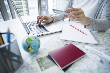 Eine Person tippt an einem Laptop und hält in der anderen Hand eine Bankkarte