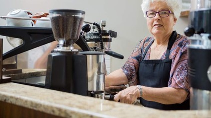 Alte Frau an Kaffeemaschine