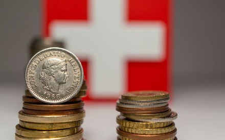 Zwei Stapel Münzen vor einer schweizer Flagge