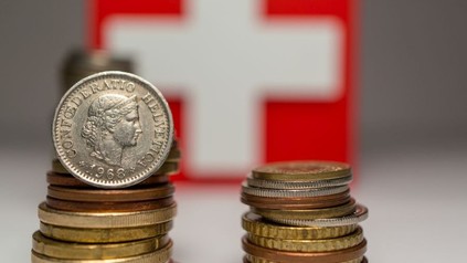 Schweizer Münzen vor einer Schweizer Fahne