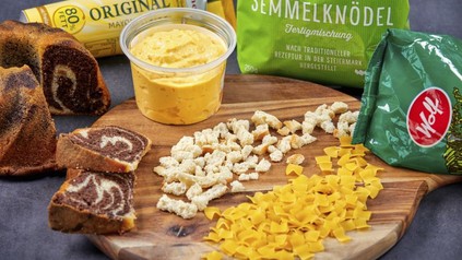 Diverse Fertigprodukte, wie Semmelknödel Fertigmischung, Mayonnaise, Senf, Kuchenmischungen und Nudeln auf einem Holzbrett