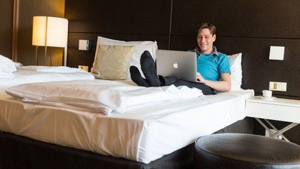 Mann auf Bett mit Laptop