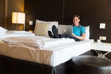 Mann auf Bett mit Laptop