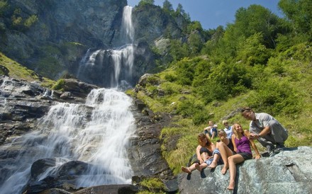 FReundesrunde macht Pause beim Wandern neben einem Wasserfall