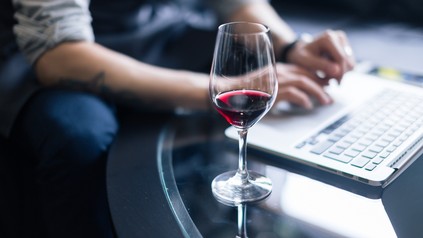 Ein Glas Wein neben einem Laptop