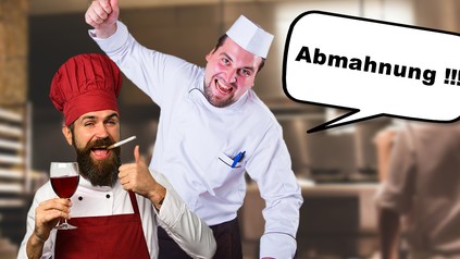 Ein Chefkoch schreit einem Koch "Abmahnung!" entgegen