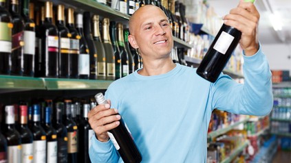 Ein Mann prüft in einem Supermarkt ein Weinetikett