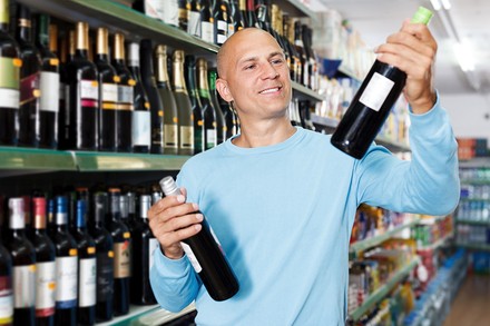 Ein Mann prüft in einem Supermarkt ein Weinetikett