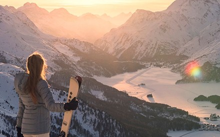 Snowboarderin blickt auf St. Moritz-See bei Sonnenaufgang