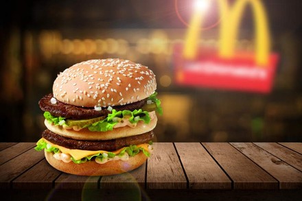 Ein Big Mac vor einem McDonaldslogo