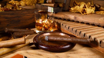 Kubanische Zigarre in Aschenbecher und Rum in Glas
