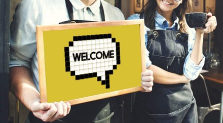 Mann hält Schild mit Inschrift „Welcome“