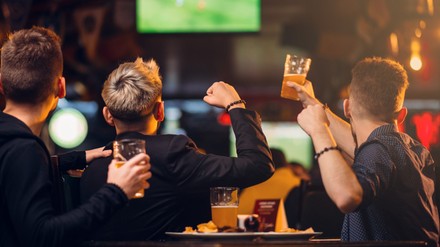 Drei Männer schauen Fußball in einer Kneipe