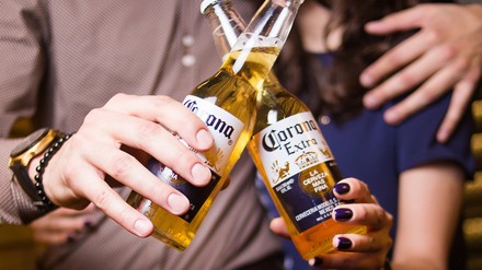 Zwei Menschen stoßen mit Corona an