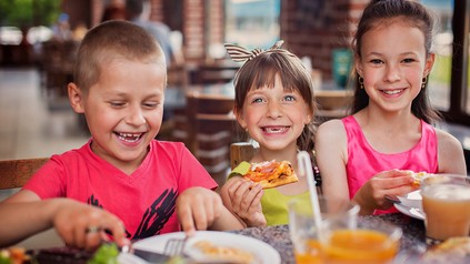 Drei fröhliche Kinder essen in einem Restaurant