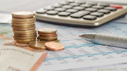 Euro-Geldscheine und Münzgeld mit Taschenrechner und Kugelschreiber