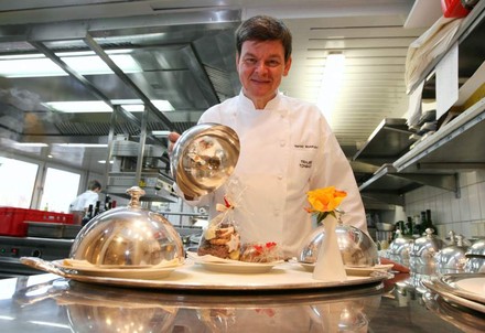 Drei-Sterne-Koch Harald Wohlfahrt posiert mit einem Tablett in der Küche des Restaurants Schwarzwaldstube