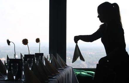 Servicekraft deckt Tisch mit Servietten