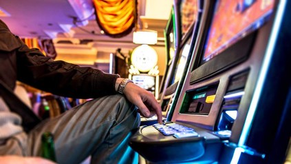 Mann mit Bier an Spielautomat