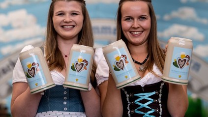 Zwei Frauen halten je zwei Bierkrüge in Händen