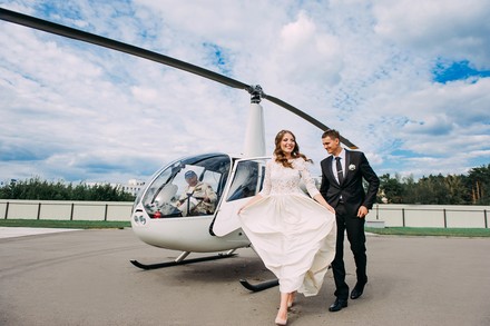 Ein Hochzeitspaar vor einem Hubschrauber mit Pilot
