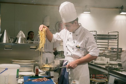 Koch nimmt Nudeln mit Händen aus Pfanne