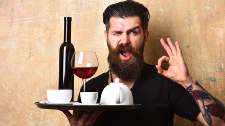 Durch gezieltes Upselling können Gastronomen ihre Umsätze steigern. (Foto: © be free – stock.adobe.com)
Kellner mit Tablett zwinkert in die Kamera