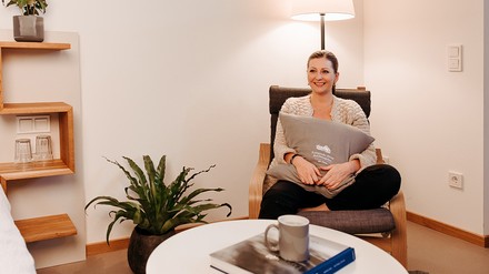 Katharina Schreiner, F&B Assistant Operations Managerin im Kempinski Hotel Berchtesgaden freut sich über die neue Wohnsituation. (Foto: © Kempinski Hotels)
Katharina Schreiner sitzt in ihrer neuen Wohnung und strahlt über das ganze Gesicht.