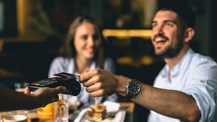 Wer als Stammkunde einen Rabatt oder ein Freigetränk bekommt, freut sich. (Foto: © cherryandbees/stock.adobe.com)
Ein Mann bezahlt im Restaurant mit Karte.