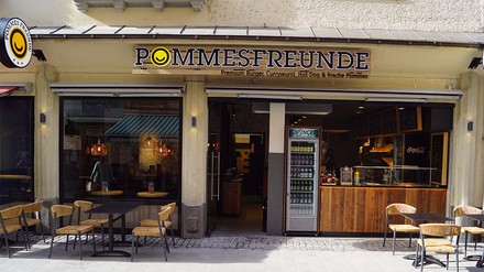 Symbolbild: Pommes Freunde in der Münchner Innenstadt (Orlandostraße) (Foto: © Pommes Freunde)
Pommes Freunde Filiale von außen mit Biertischen und Bierbänken