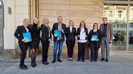 Axel Hausmann (4. v. l., Residence Manager) mit den Abteilungsleiterinnen im Hotel Elbresidenz und Ole Hartjen (rechts außen, Vorstand Operations Toskanaworld AG) bei der Übergabe des Awards (Foto: © Petra Lulei/Toskanaworld AG)
Übergabe des Awards vor dem Hotel Elbresidenz