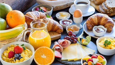 Semmel, Wurst und Ei oder doch lieber Croissant, Marmelade und Müsli zum Frühstück? (Foto: © juefraphoto/stock.adobe.com)
Ein reich gedeckter Frühstückstisch mit Wurst- und Käseplatte, Brötchen, Ei, Müsli, Obst und Orangensaft.