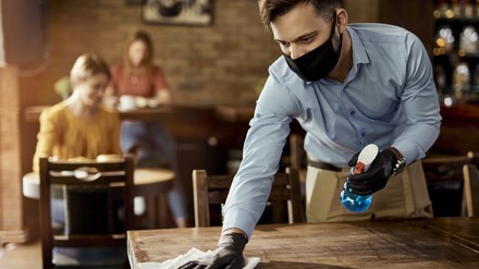 Vorläufige Papiere für die Bund-Länder-Runde sahen grundsätzlich eine Fortführung der bisherigen Maßnahmen vor. (Foto: © Drazen/stock.adobe.com)
Kellner reinigt Tisch