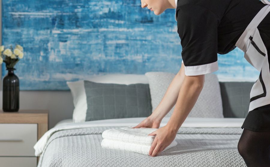 Stubenmädchen legt Handtücher auf dem Gästebett zusammen